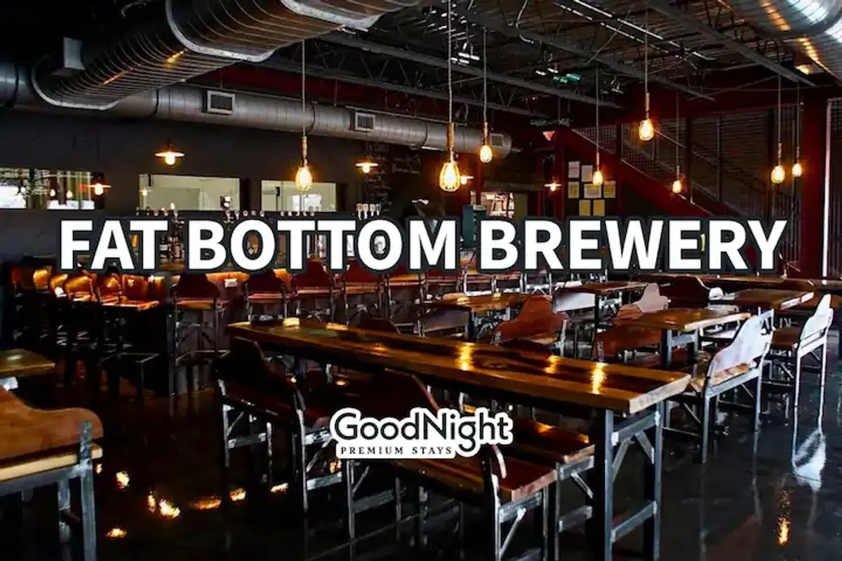 A lively interior of a popular Nashville venue featuring long communal wooden tables, a bustling bar area, and hanging light fixtures. The space is filled with people socializing, tasting craft beers, and enjoying live music events, highlighting the communal aspect of Nashville’s entertainment scene.