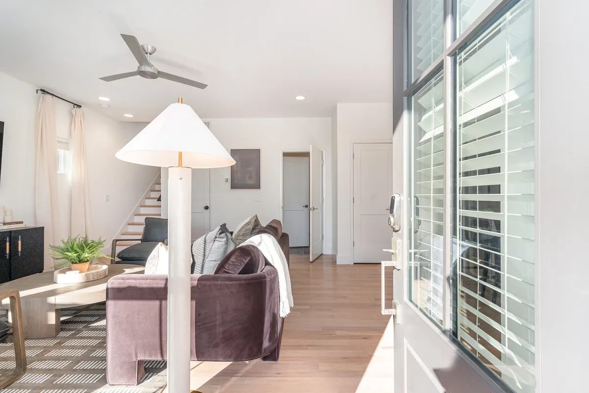 A cozy living room with a comfortable sofa, lamp, coffee table, and large window. The space invites relaxation, reading, or socializing in a peaceful, inviting atmosphere.