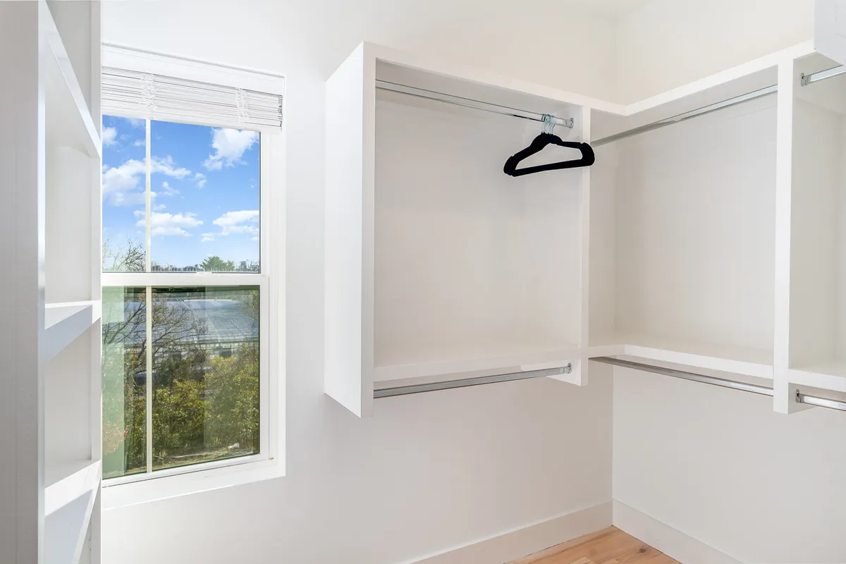 A spacious, empty closet with a window that brings in natural light, offering ample room for organizing and storing belongings. The closet feels open and inviting, enhancing the sense of space and order.